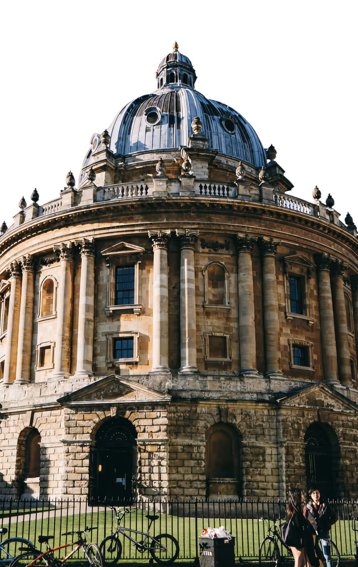 A prominent, eye-level view of the Radcliffe Camera in Oxford, a large circular building in the English Baroque style, featuring a high, dark lead-covered dome.
