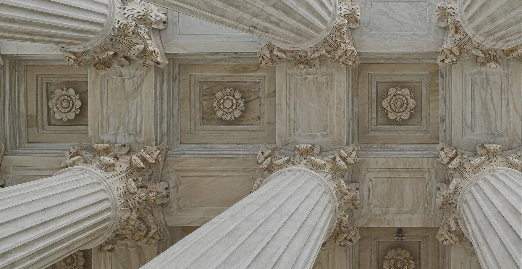 Dramatic upward view of a coffered, light-colored marble ceiling